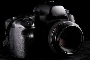 Professional modern DSLR camera low key image - Modern DSLR camera with a  lens on