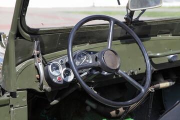 Old steering wheel and analog appliances dashboard in interior of old khaki retro soviet military...