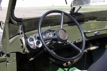 Steering wheel and dashboard in interior of old khaki vintage soviet military AWD car close up at Sunny day