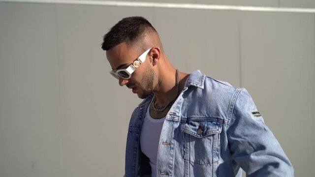A young Spanish man with tattoos a chain and stylish sunglasses posing shot in 4K