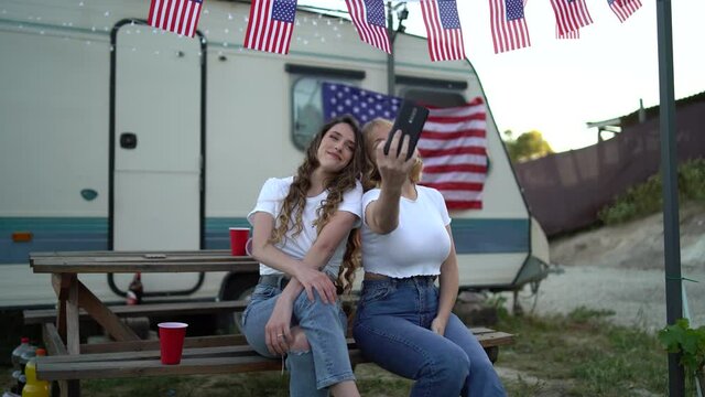 Spanish friends doing a selfie near a camp trailer with an American flag shot in 4K