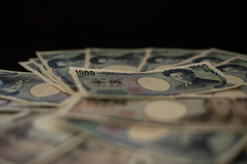 Blurred focus of pile of Japanese money in 1000 yen bills and 10000 yen bills on black background in soft focus
