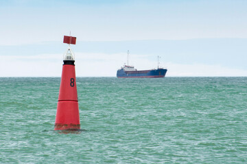 Red marine buoy in the fairway. Navigational signs. Escorting the ship to the port.
