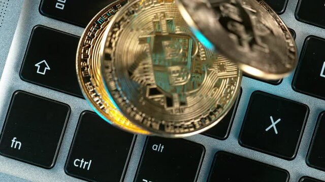 Close-up of golden bitcoins physical coin falling on computer keyboard. super slow motion at 1000 fps