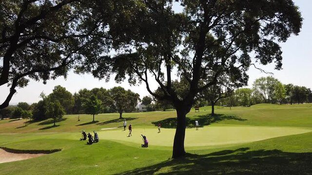 Un grupo de jugadores de golf espera en el green su turno para terminar la partida