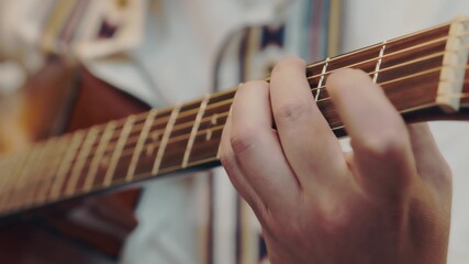 male hand rearranges chords on acoustic guitar close up.