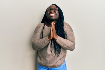 Young black woman with braids wearing casual clothes and glasses begging and praying with hands...