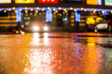 Rainy night in the parking shopping mall, the light from the headlights of a car traveling towards....