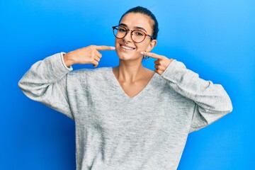 Young hispanic woman wearing casual clothes smiling cheerful showing and pointing with fingers teeth and mouth. dental health concept.