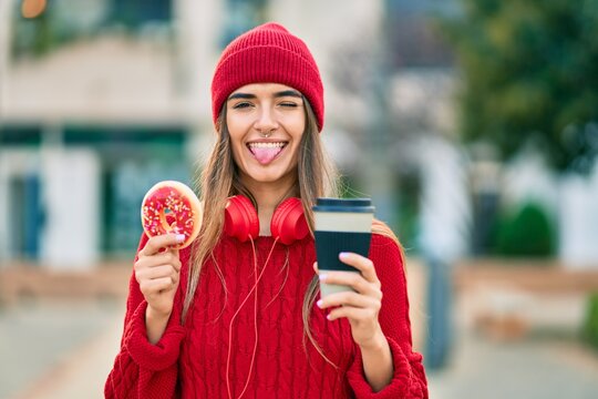 Young hispanic woman having breakfast using headphones at the city.