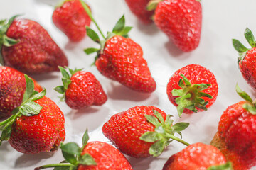 Fototapeta na wymiar A lot of red ripe tasty strawberries lie on a white background