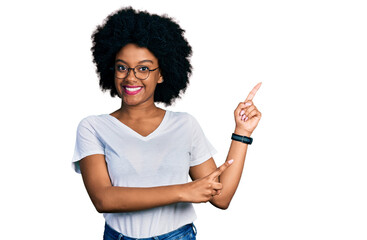 Young african american woman wearing casual white t shirt smiling and looking at the camera pointing with two hands and fingers to the side.