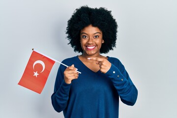 Young african american woman holding turkey flag smiling happy pointing with hand and finger