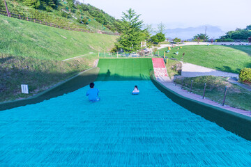 公園でそり遊びをする親子