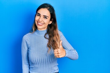 Fototapeta premium Young hispanic girl wearing casual clothes doing happy thumbs up gesture with hand. approving expression looking at the camera showing success.
