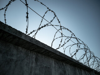 Barbed wire on fence on blue sky background