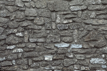 Wall of old ancient fortress. Stony wall texture. Medieval broadwall surface. Old antique stony bailey. Ancient castle wall.  Rubble face. Ruin wall.
