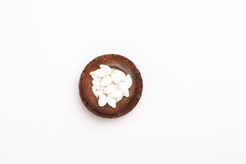 Heap of pumpkin seeds in bowl on white background