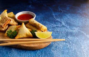 Asian finger food, Dim sum spring rolls with spicy chilli sauce on a rustic table top.