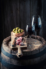 Wine in glass and appetizer on old wooden barrel
