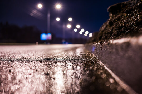 Rainy Night In The Big City, The Empty Highway With Lanterns. Close Up View Of A Level Curb On The Road