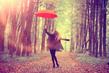 young woman dancing in an autumn park with an umbrella, spinning and holding an umbrella, autumn walk in a yellow October park