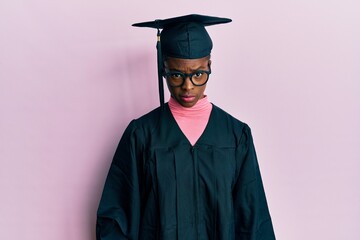 Young african american girl wearing graduation cap and ceremony robe skeptic and nervous, frowning upset because of problem. negative person.