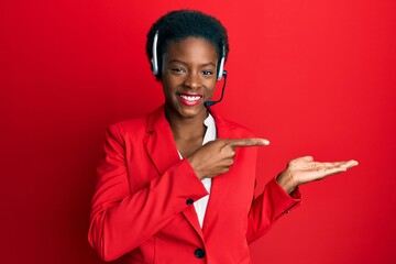 Young african american girl wearing call center agent headset amazed and smiling to the camera...