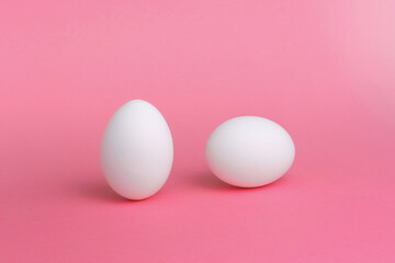 White eggs on a pink background. The concept of minimalism. Side view. A card with a copy of the place for the text.