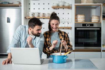 Young happy couple in the kitchen man teasing his girlfriend how she dont know to cook when she...