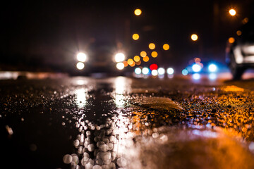 Rainy night in the big city, the cars traveling towards the headlights illuminate the road. Close up view from the level of the dividing line
