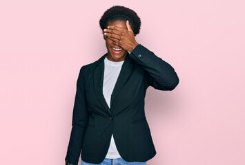 Young african american girl wearing business clothes smiling and laughing with hand on face covering eyes for surprise. blind concept.