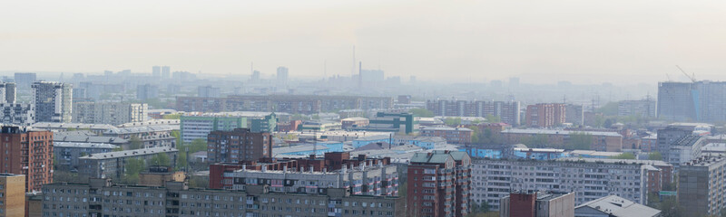 Fototapeta premium Landscape of the industrial area of the city. Residential buildings, production chimneys, haze, smog. Panoramic view.
