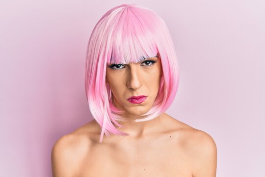 Young man wearing woman make up wearing pink wig depressed and worry for distress, crying angry and afraid. sad expression.