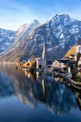 Fototapeta na wymiar VIew of beautiful Hallstatt lake and famous church during morning sunrise in early spring
