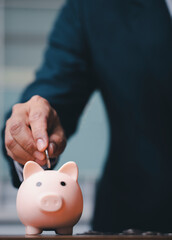 business man putting coins into the piggy bank.