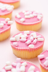 Colorful cupcakes on a pink background.