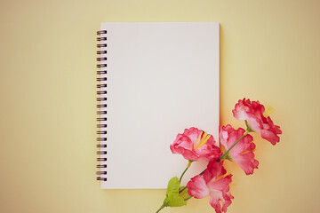 Spiral Notebook or Spring Notebook in Unlined Type and Red Flower on Pastel Yellow Minimalist Background. Spiral Notebook Mock up on Center Frame in Vintage Tone