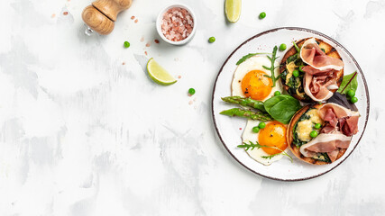 Fototapeta na wymiar grilled bun with spinach and cheese, asparagus, jamon, ham, prosciutto and fried egg. fresh juice, healthy breakfast. Copy space. Healthy food concept. Banner