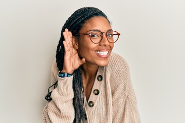 African american woman wearing casual clothes and glasses smiling with hand over ear listening and...