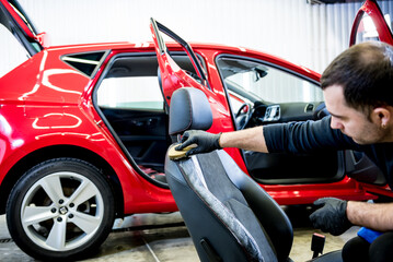Fototapeta na wymiar Car service worker cleans a car seat with a special brush