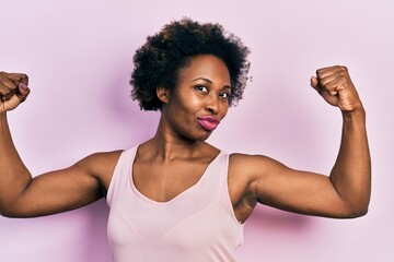 Young african american woman wearing casual sleeveless t shirt showing arms muscles smiling proud....