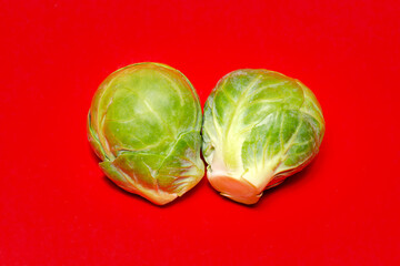 A pair of delicious green Brussel Sprouts isolated on ared background. Healthy eating, bright colorful vegetables.