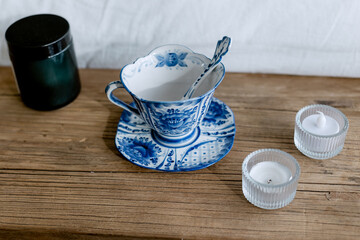Stylish mug with blue patterns stands in the interior on a wooden candle shelf