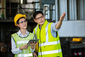 asian men and women engineer worker standing at factory talk about project with her uses digital tablet. heavy industry factory concept.