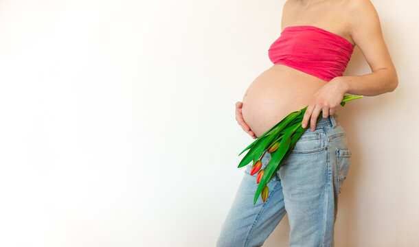 Pregnant belly with a bouquet of flowers. The joy and happiness of motherhood pregnant girl in anticipation of the baby.