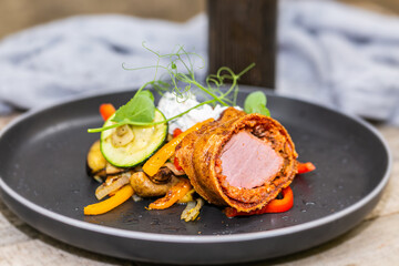 Grilled pork tenderloin in a roll with fresh vegetables and herbs.Close up