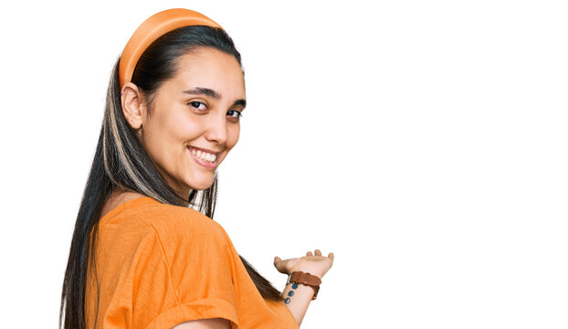 Young hispanic woman wearing casual clothes inviting to enter smiling natural with open hand