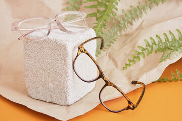 eye glasses on a concrete podium on a brown background, trend composition, stylish eye glasses on a...