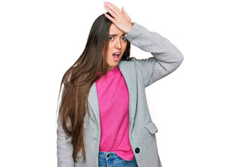 Young hispanic girl wearing business clothes surprised with hand on head for mistake, remember...